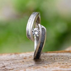 two wedding rings on top of each other with a diamond in the middle and an engraved band