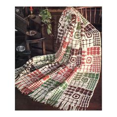 a blanket sitting on top of a wooden floor next to a chair and table with a potted plant