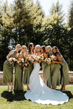 a group of women standing next to each other on top of a lush green field