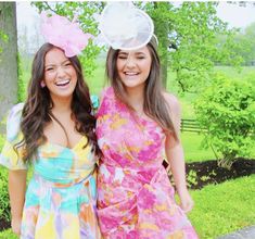 two women standing next to each other in front of trees and grass with one woman wearing a flowered dress