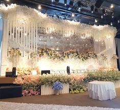 a stage set up with flowers and chandelier hanging from it's ceiling