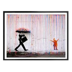 a person holding an umbrella in front of a wall with rainbow streamers on it