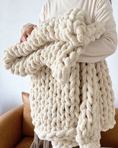 a person holding up a large chunky knitted blanket over their head and hands