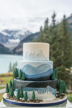 a three tiered cake decorated with trees and mountains