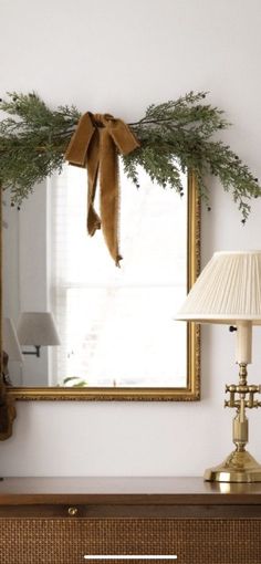 a christmas wreath is hanging on the wall above a dresser with a lamp and mirror