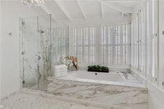 a white bathroom with marble floors and walls