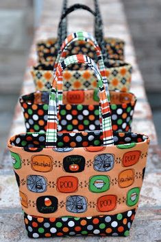 three purses are lined up on a table with polka dots and black, orange, green, and white designs