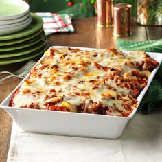 a white casserole dish filled with lasagna sauce and cheese on a wooden table