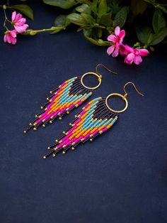 a pair of colorful beaded earrings sitting on top of a table next to flowers