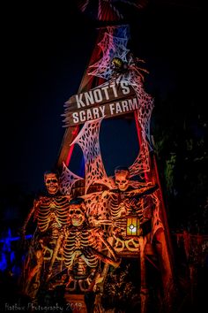 an illuminated sign for knotty's scary farm with skeletons on it at night