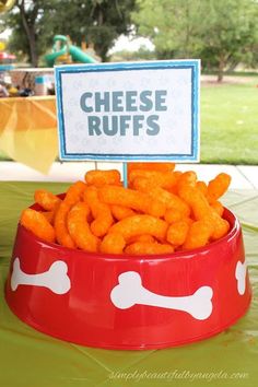 a red bowl filled with cheetos sitting on top of a table