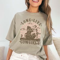 Yeehaw, Cowgirl! Ready to celebrate the spirit of the West with style and flair? Lasso up the "Long Live Cowgirls" Comfort Color Tee – the perfect tribute to the fearless and fabulous women of the rodeo. Crafted from premium Comfort Color fabric, this tee offers unbeatable comfort and durability, perfect for all your Western adventures. The bold design proudly proclaims "Long Live Cowgirls," honoring the strength, independence, and spirit of the women who ride with the wind. Whether you're breaking in a new bronco or two-stepping under the stars, this tee is your go-to choice for casual comfort and Western charm. Its relaxed fit ensures you stay cool and carefree, whether you're roping cattle or enjoying a well-deserved break at the saloon. From early morning trail rides to late-night barn Graphic Print Crew Neck Tops For Western-themed Events, Crew Neck Top With Graphic Print For Western-themed Events, Western-themed Graphic Print Cotton Tops, Cotton Graphic Print Top For Western-themed Events, Relaxed Fit Tops For Country Concerts, Retro Crew Neck Tops For Western-themed Events, Relaxed Fit Graphic Print Tops For Western-themed Events, Vintage Tops For Western-themed Events, Crew Neck T-shirt For Western-themed Spring Events