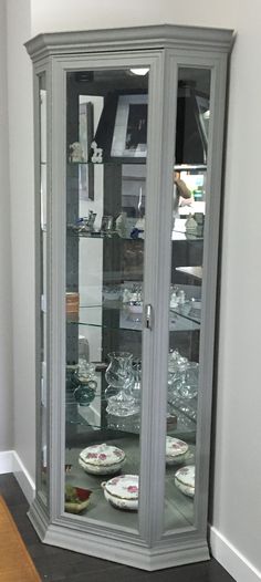 a china cabinet with glass doors and plates on it's shelves in the corner