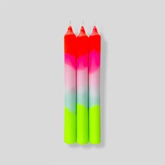 two neon colored candles sitting next to each other