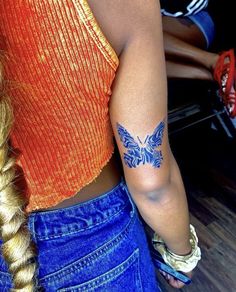 a woman with a butterfly tattoo on her left arm and right arm behind her back