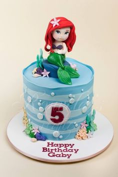 a birthday cake with a little mermaid sitting on it's top and the number five