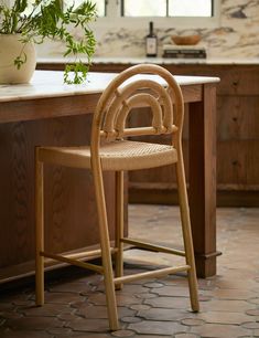 a wooden chair sitting in front of a counter top next to a potted plant