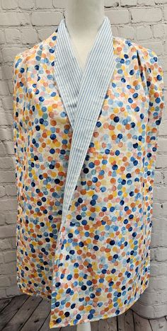 a white mannequin wearing a blue and yellow polka dot print top with an open neck