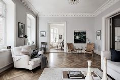 a living room filled with furniture and a chandelier hanging from the ceiling over a wooden floor