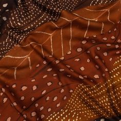 an orange and brown patterned fabric with white dots on the top right corner is laying down