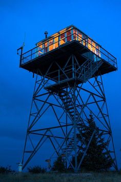 a tall tower that has a lit up window on it's side at night