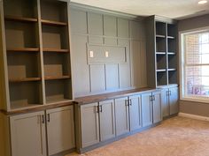 an empty room with built in bookshelves and cabinets