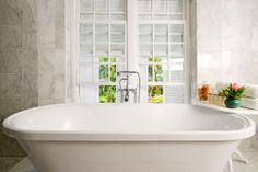 a white bath tub sitting next to two windows