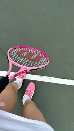 a person holding a tennis racket on a court with the number 20 painted on it