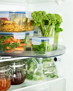 an open refrigerator filled with lots of different types of vegetables and food in plastic containers