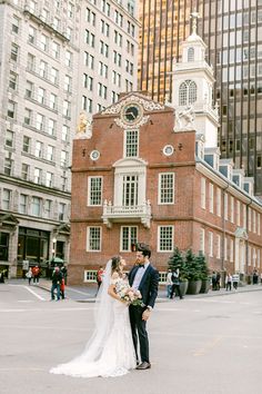 a bride and groom standing in front of an old building with tall buildings on either side