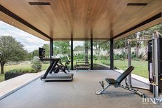 an indoor gym with treadmills, exercise machines and other equipment in front of large windows