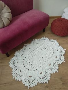 a white crocheted doily sitting on top of a wooden floor next to a pink couch