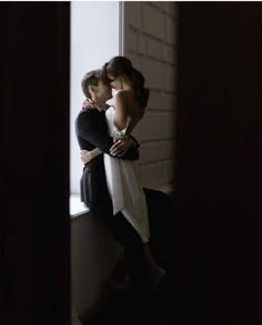 two women standing next to each other in front of a window with their arms around each other