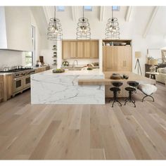 a large kitchen with wooden floors and white counter tops, along with an island in the middle