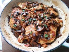 a pan filled with chicken and mushrooms covered in sauce