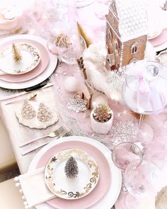 the table is set with pink and white plates, silverware, and other decorations