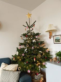 a small christmas tree is in the corner of a living room with ornaments on it