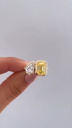 a person holding an engagement ring with a yellow and white diamond in it's middle