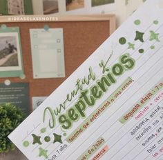 a hand holding up a paper with spanish writing on it in front of a bulletin board