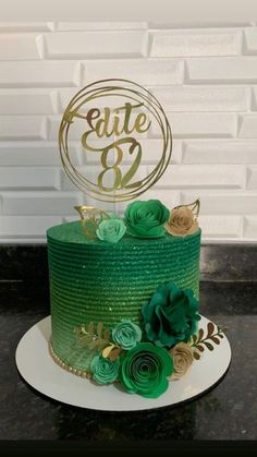 a green and gold cake with flowers on top