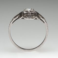 This lovely circa 1930s ring features an 18K white gold gallery and is finished with a 14K white gold shank. The ring features a pierced and engraved design with milgrain details and is centered with one (1) round transitional brilliant cut diamond. The ring measures 18.4mm at the top, rises 4.3mm above the finger, tapering to 1.6mm wide and 1.2mm thick at the base of the shank. This ring is currently a size 6. The ring shows gentle overall wear. Formal 14k White Gold Filigree Ring, Formal Platinum Rings With Classic Cut, Platinum Rings For Formal Occasions With Classic Cut, Formal Classic Cut Platinum Diamond Ring, Classic Formal Filigree Ring In Diamond White, Classic Filigree Ring With Intricate Design For Formal Events, Classic Filigree Ring With Intricate Design For Formal Occasions, Vintage Engraved Ring With Single Diamond For Formal Occasions, Classic Engraved Ring With Single Diamond