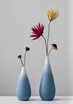 two vases with flowers in them sitting on a table