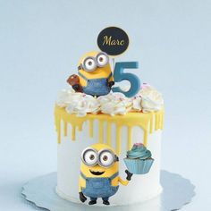 a white cake with yellow icing and two minion figurines on top