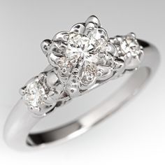 a white gold ring with three diamonds on the sides and an intricate design in the middle