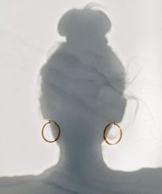 the shadow of a person's head and earring on a white background with shadows