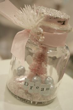 a glass jar filled with white and pink stuff on top of a table next to a ribbon