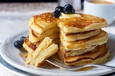 a stack of pancakes on a plate with blueberries and syrup