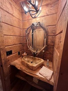 a rustic bathroom with wooden walls and wood flooring, an antler's head hanging over the sink