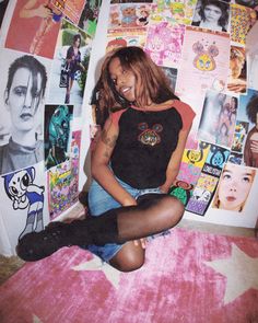 a woman sitting on top of a bed covered in posters