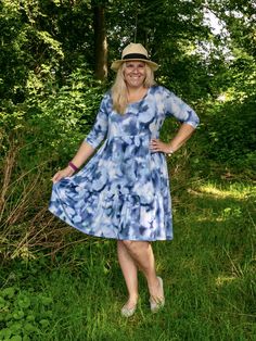 a woman standing in the grass wearing a dress and hat